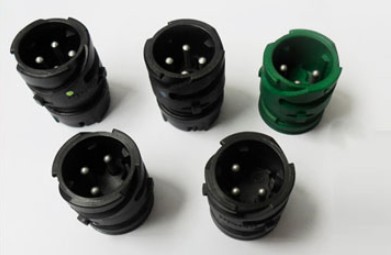 Black and green circular sensor housings with pins