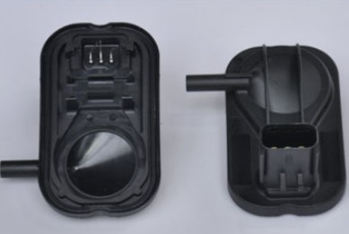 A black sensor housing with molded-in pins